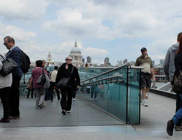 Image shows pedestrians using bridge in London featuring green glass guardrail to illustrate the work of laminated glass suppliers Kite Glass Weybridge