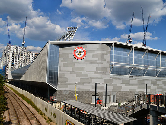 Sunny scene of Brentford Football Club from the train tracks to illustrate an example of work by architectural glass manufacturer Kite Glass Weybridge